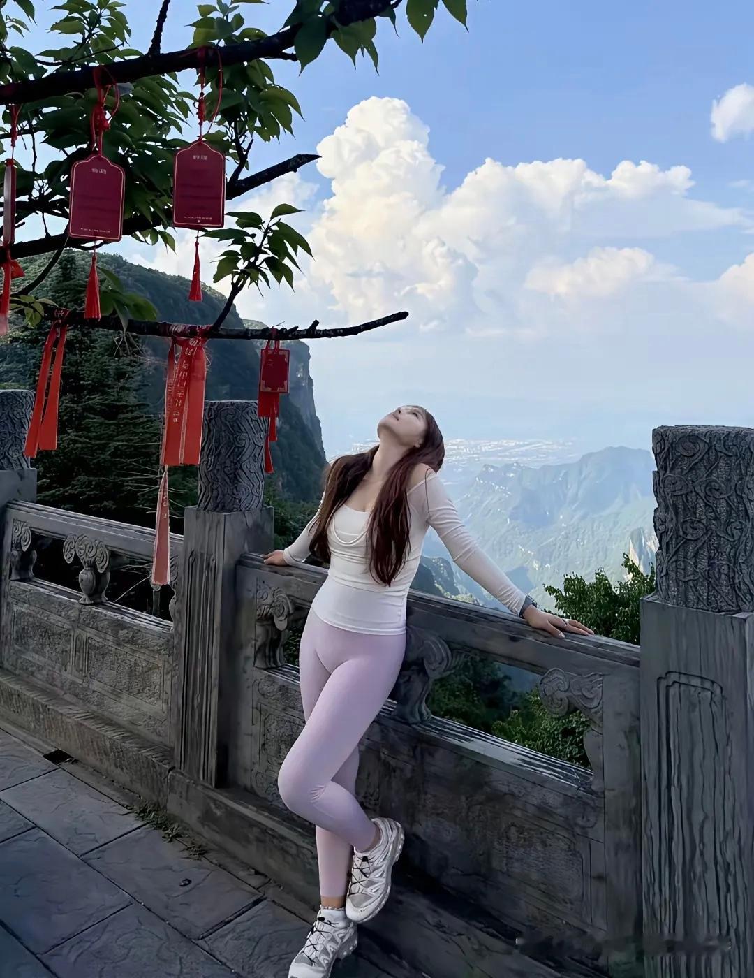 这姑娘在山顶上靠着栏杆，欣赏风景。