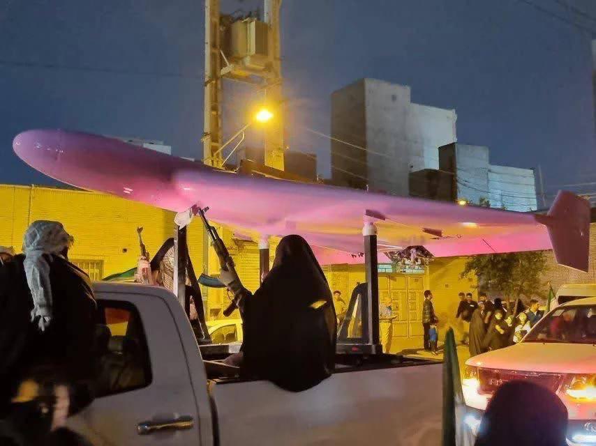 伊朗女性与伊朗革命卫队战士正在用一架粉色的 Shahed-136 自杀式无人机进