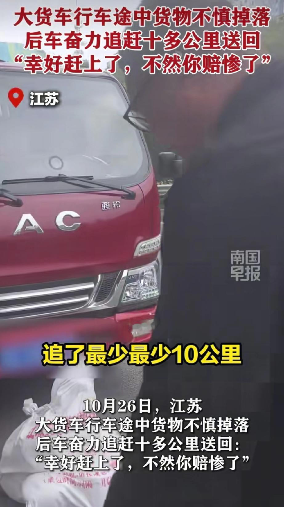 江苏，一辆大货车上的货物掉落至马路上。后面小车的司机瞧见后，赶忙停车拾起地上的货