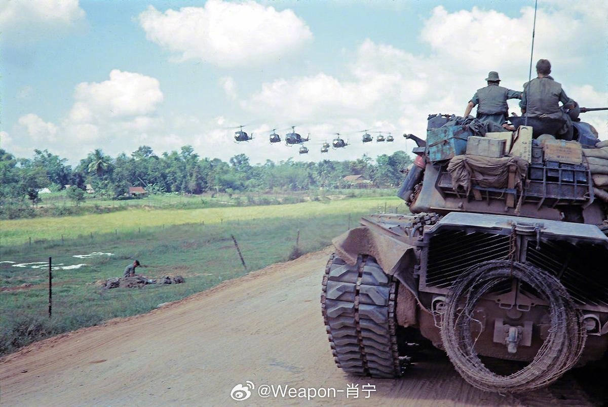 照片中的历史 越战期间，美军M48A3坦克 的乘员们注视着 UH-1 休伊直升机