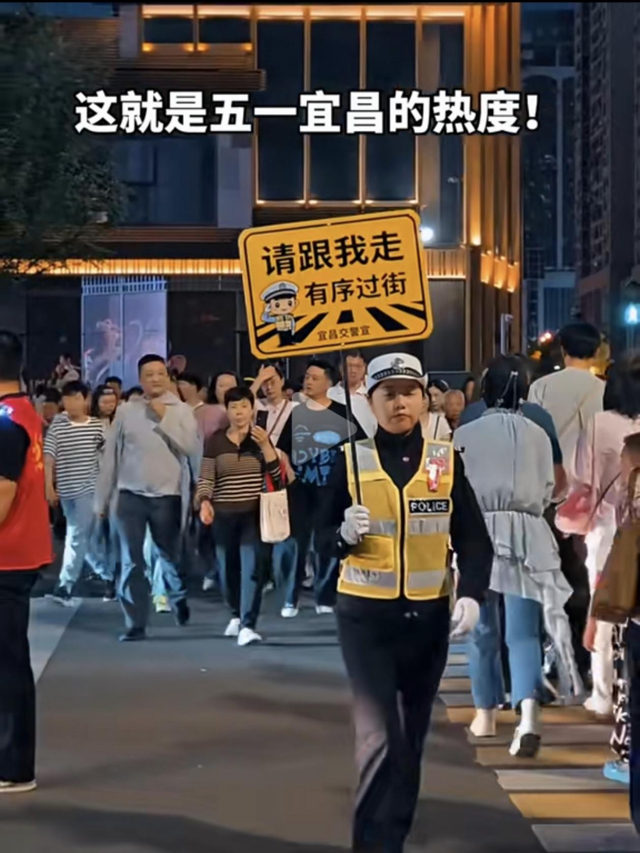 五一假期的宜昌滨江，人山人海，连过个街都困难，组成人墙和带领过马路的交警，带给游