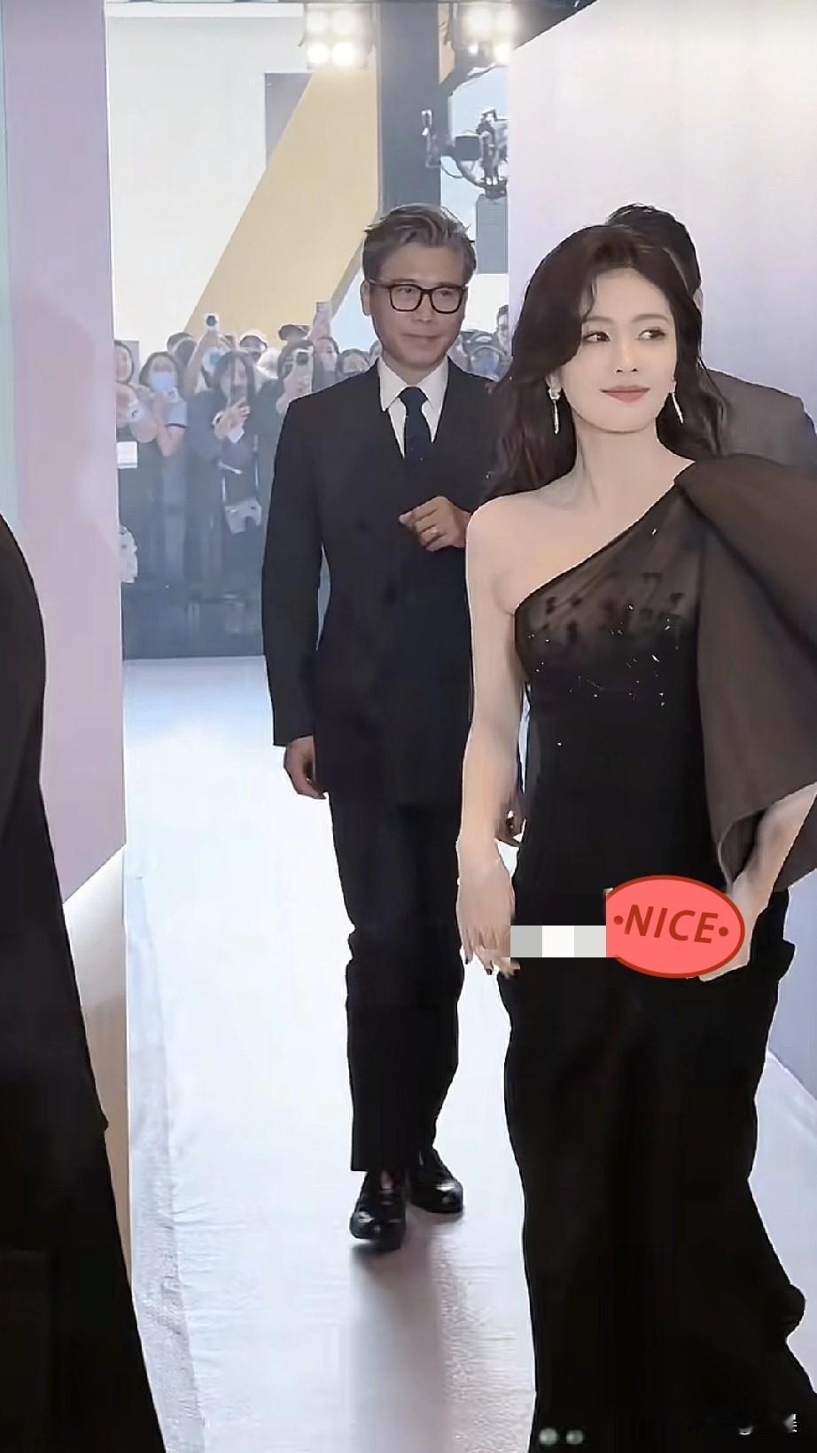 在活动现场的通道中，白鹿身着一袭优雅的黑色单肩礼裙，搭配精致的耳饰与高跟鞋，气质