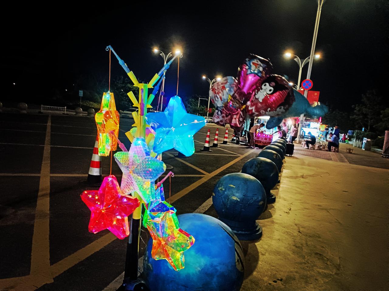 夜色街边，彩灯星光闪闪，灯火人流热闹，海滨夜市暖意融融。