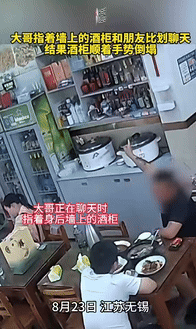 “这下说不清了！”江苏无锡，一男子指着饭店墙上的酒柜，和好友比划聊天时，酒柜突然