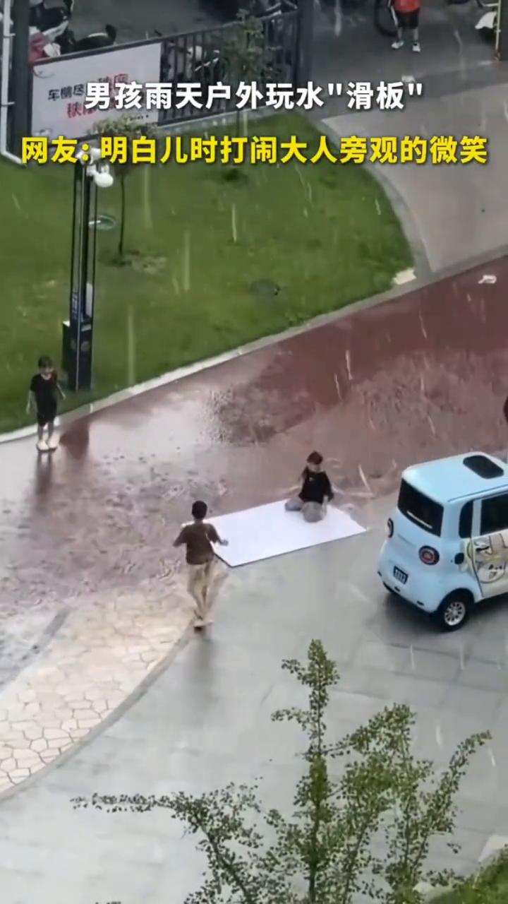 男孩雨天户外玩水"滑板"。
网友：明白儿时打闹大人旁观的微笑。终于明白，小时候一