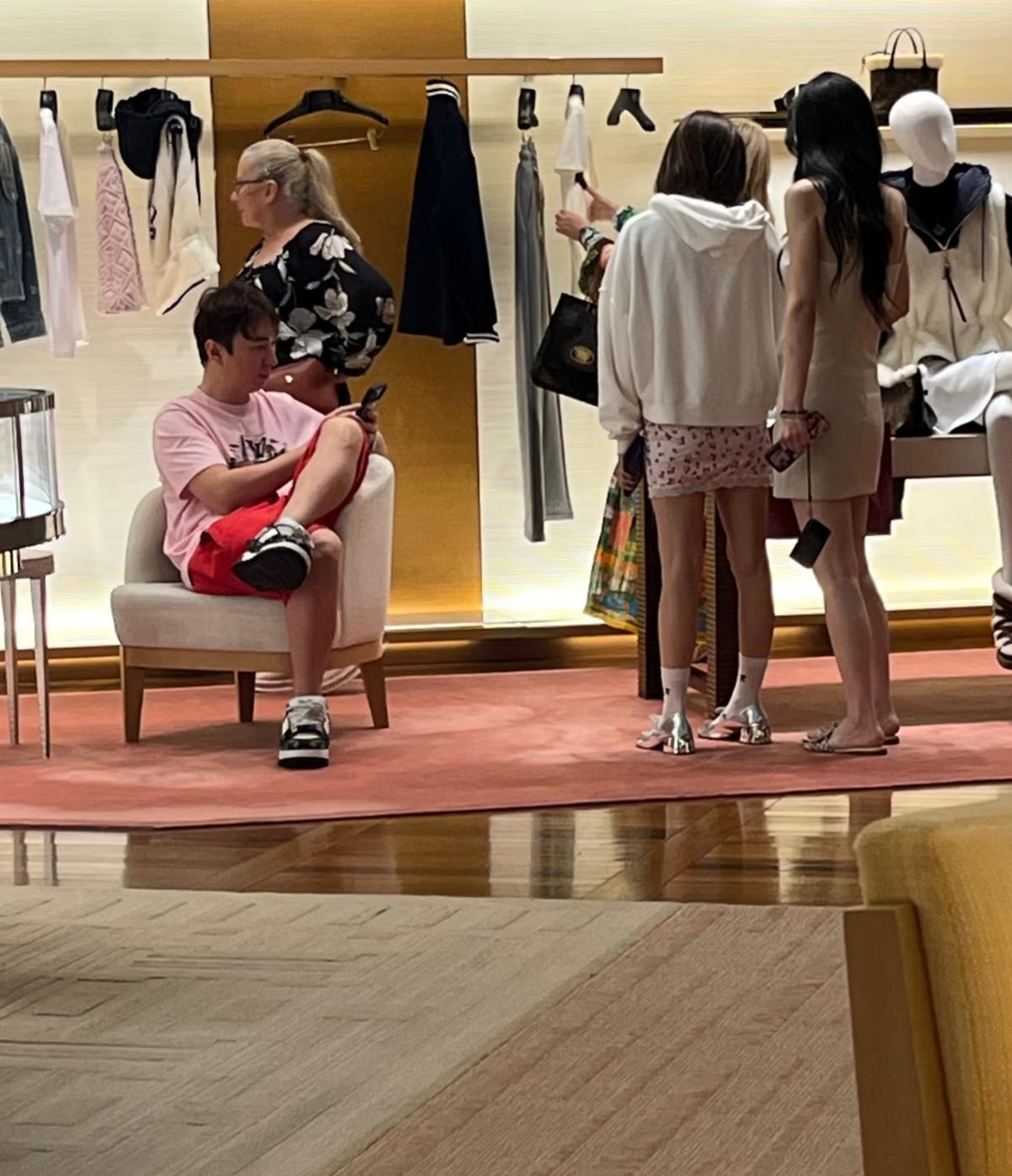 王思聪带女生在新加坡购物。王校长坐那里刷手机等女生挑选衣物，主打一个有耐心