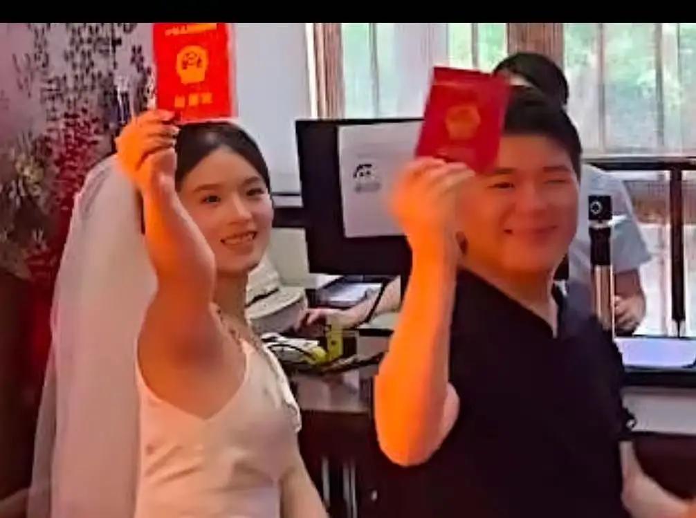 七夕的晨光里，杭州民政局门口排着长队。一对年轻情侣格外显眼，倒不是捧着玫瑰或单膝