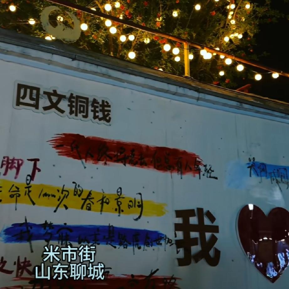 聊城米市街的夜，真叫人挪不开眼！藤蔓上挂满青葡萄，像一串串翡翠珠子垂在老墙边；暖