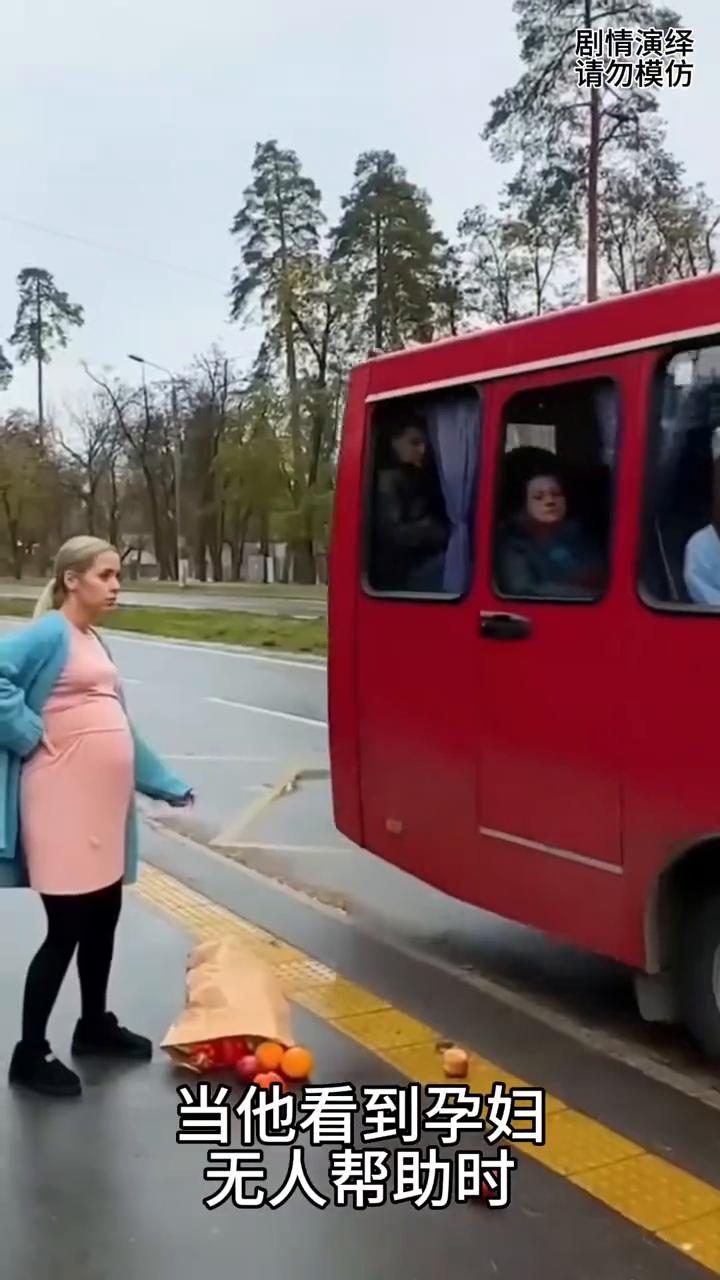 司机帮助孕妇捡起地上掉的水果。
一位孕妇准备乘坐公交车，这时乘客上车匆忙把她的手