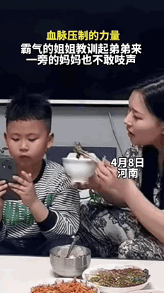 近日，河南，弟弟吃饭时只顾玩手机不愿意吃饭，妈妈端着碗把饭喂到嘴边:“来，儿子吃