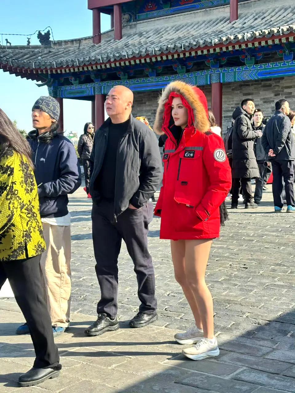 游览西安城墙的谷爱凌，上身穿着一件中国红的羽绒服，但是却光着腿。这身穿搭很特别，