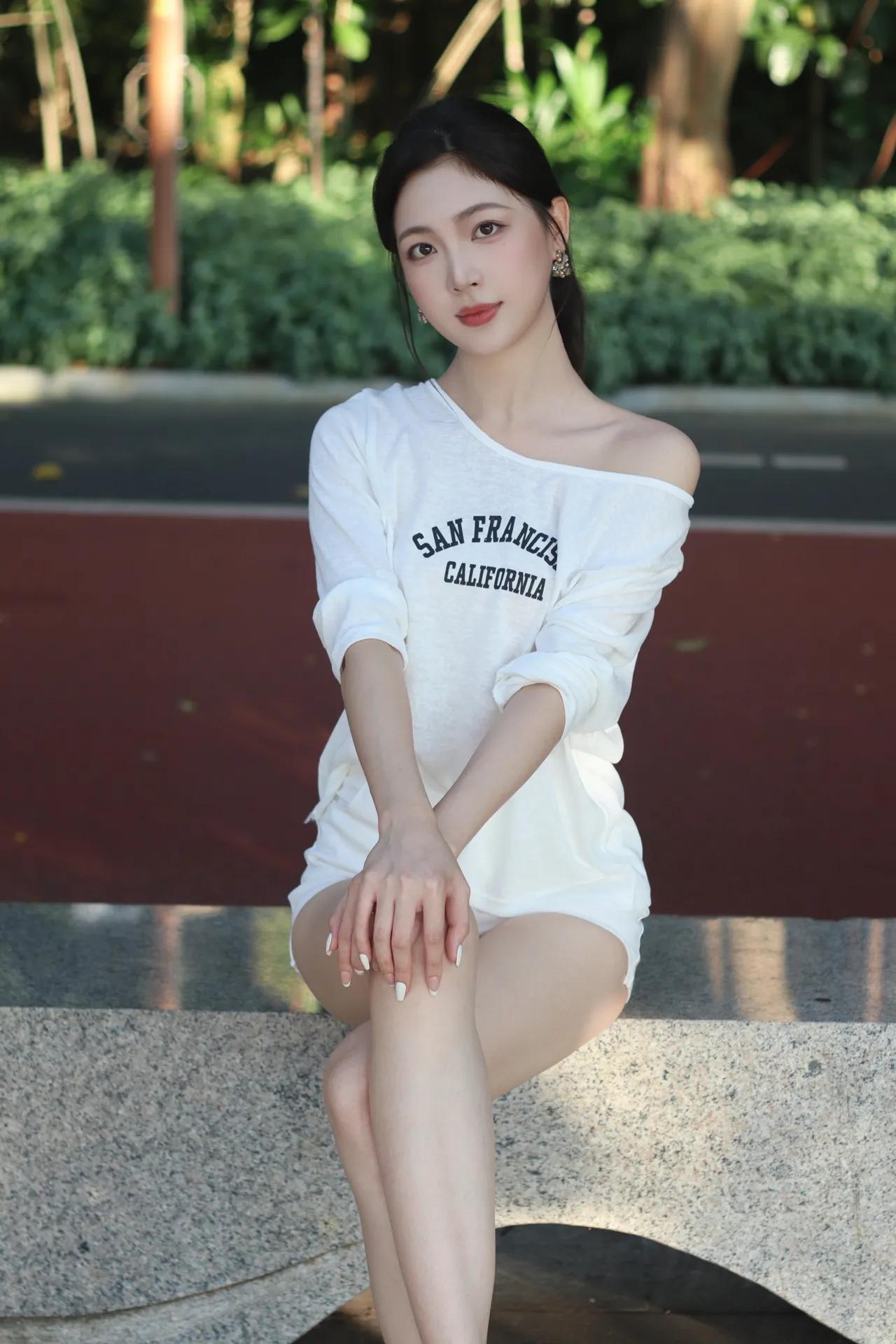 阳光明媚的午后，坐在公园长椅上，穿着“旧金山加州”的白色长袖T恤，享受宁静时光。