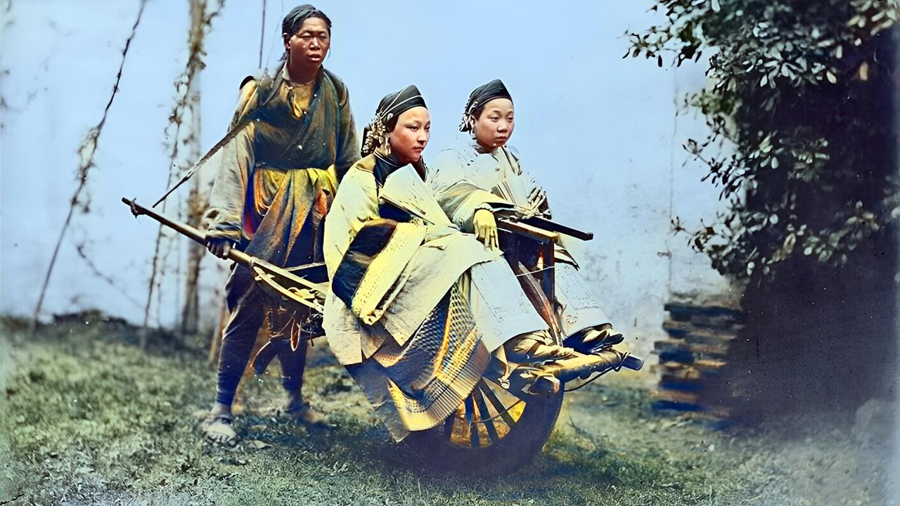 1875年，一位光脚的车夫，用独轮车推着两个打扮得漂漂亮亮的女子去赶集。

坐着