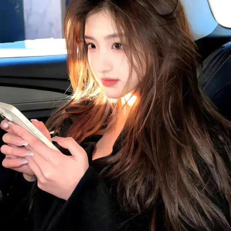 温柔灯光下，少女手拿手机，长发飘逸，尽显甜美气质。