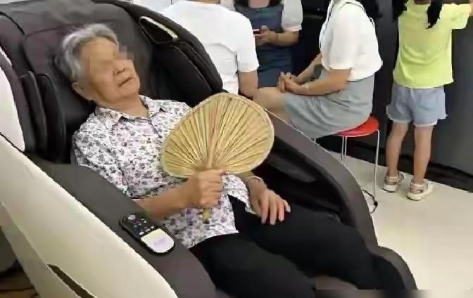 商场一楼那排按摩椅边上，经常坐着个六十三岁的老太太，一到夏天就拎着个小马扎准时打