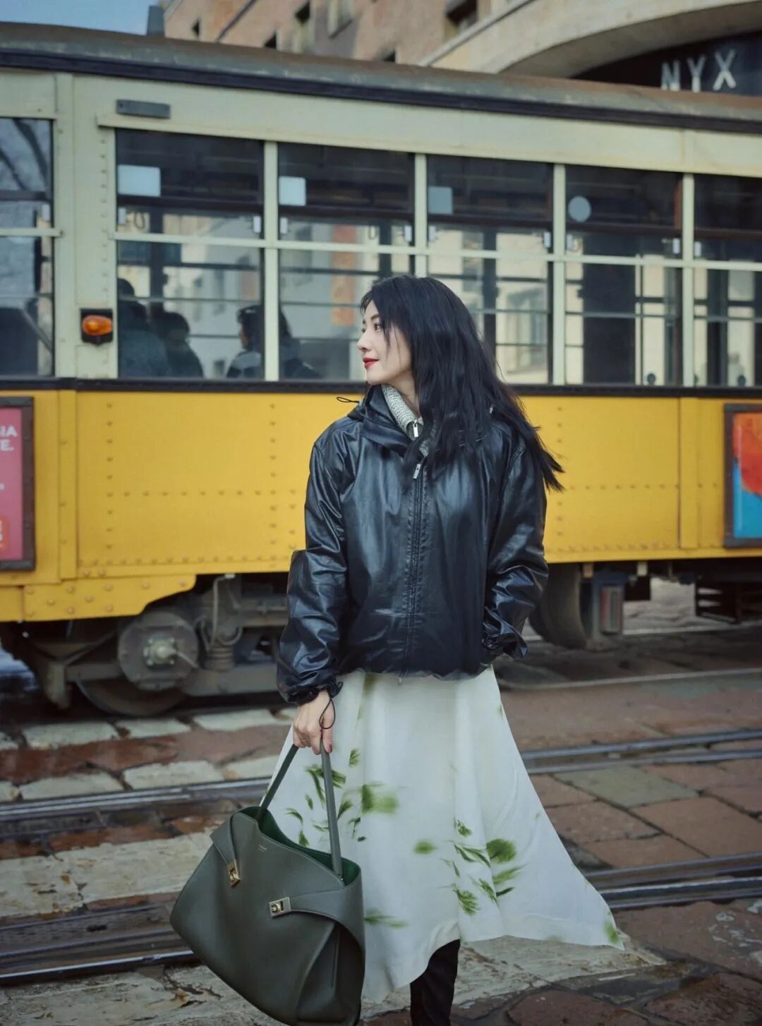 整体搭配采用材质与风格混搭，黑色亮面夹克酷飒，水墨印花裙雅致，再以同色系包包呼应