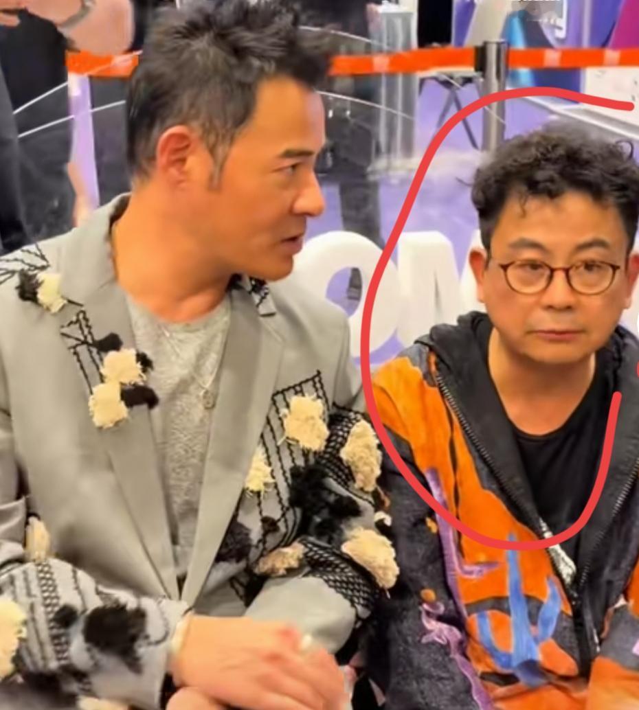 两个男人坐在一起，一个穿花衬衫，一个穿橙色外套。他是和星爷一起演的逃学威龙吗？也