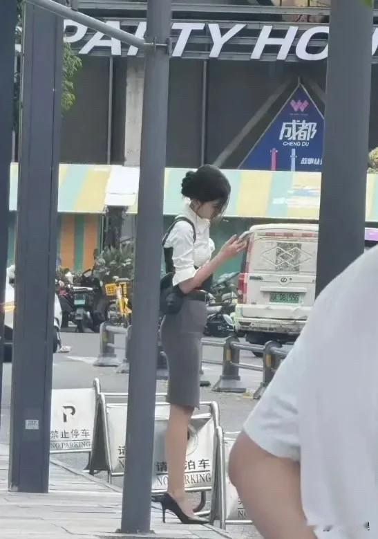 一个穿裙子的女生在看手机。