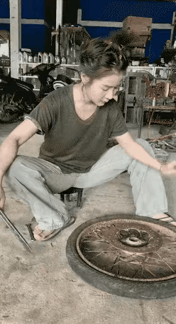 年纪不大的女工人修车，左手用钎子顶住轮胎轮圈内侧，右手拿铁板去砸钎子，就这一下用