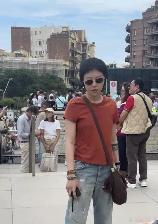 王菲女儿窦靖童戴着墨镜，穿着橙色上衣和浅蓝色牛仔裤，十分舒适惬意，松弛感拉满。 