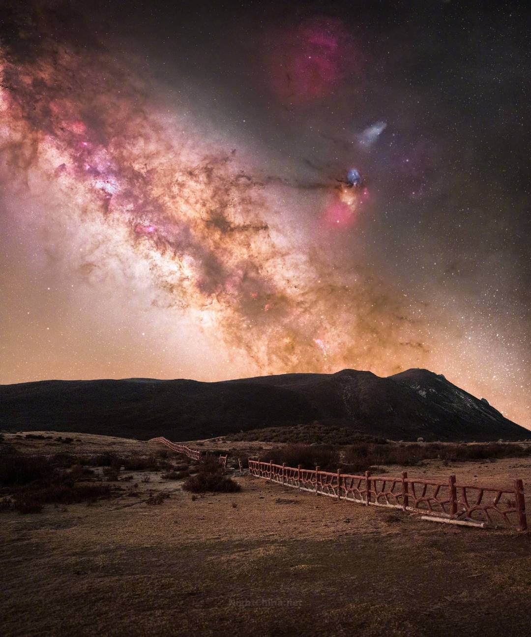 那条星河从山脊后探出身来，玫瑰色的星云如烟如霞，金橙色的银心将整片苍穹染得通透。
