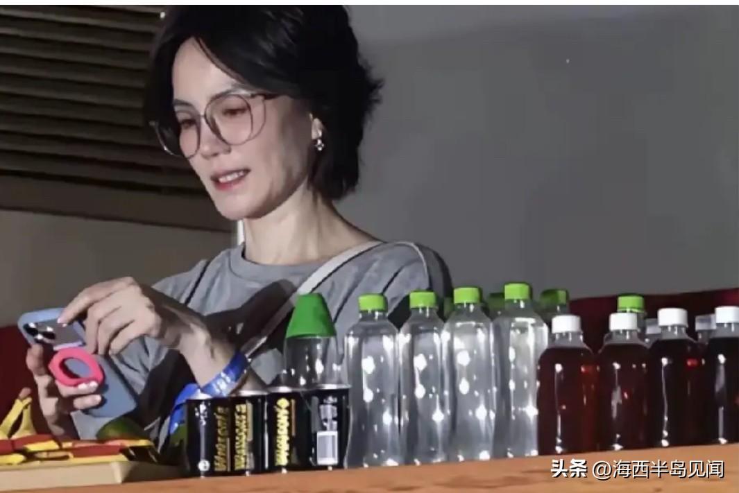 这是王菲出席那英演唱会在后台的一张留影。桌上的矿泉水品牌标签全部被王菲提前撕的干