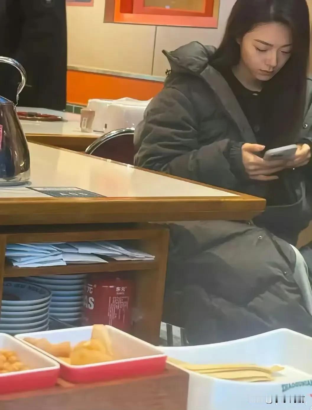 独自一人在餐厅，低头玩手机，享受静谧时光。