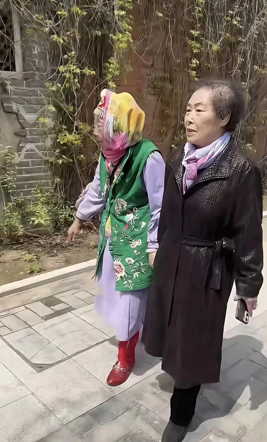 马玉琴打扮得五颜六色、还油光水滑的，老姐俩关系是真铁，一路上手牵手、肩并肩走。
