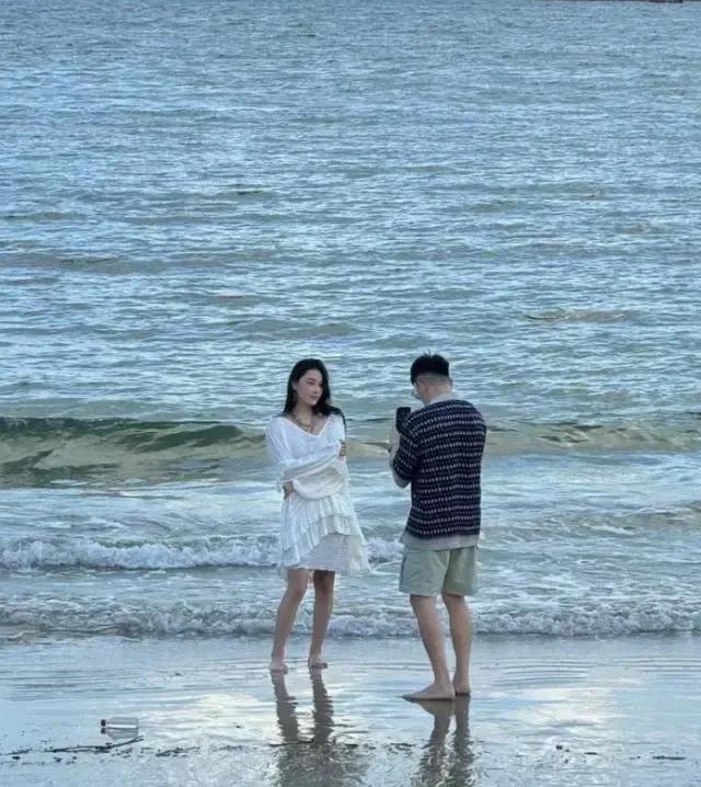 近日，张馨予与老公何捷携手漫步在海边游走，她身着一袭洁白长裙，长发随风轻舞，全身