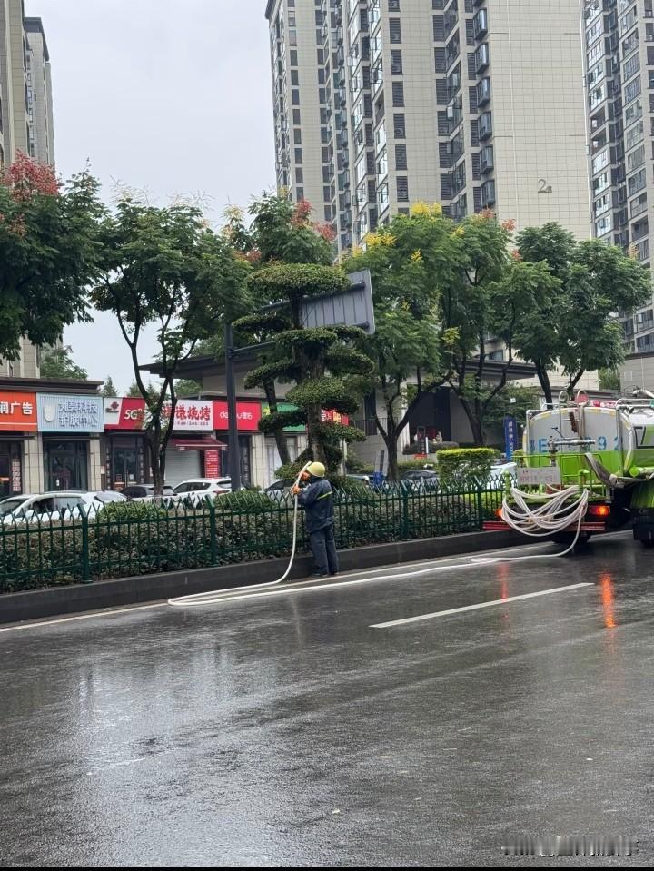 下雨天为什么还要给绿植浇水？
今天下瓢泼大雨，等车的时候看到这位师傅冒着大雨还在