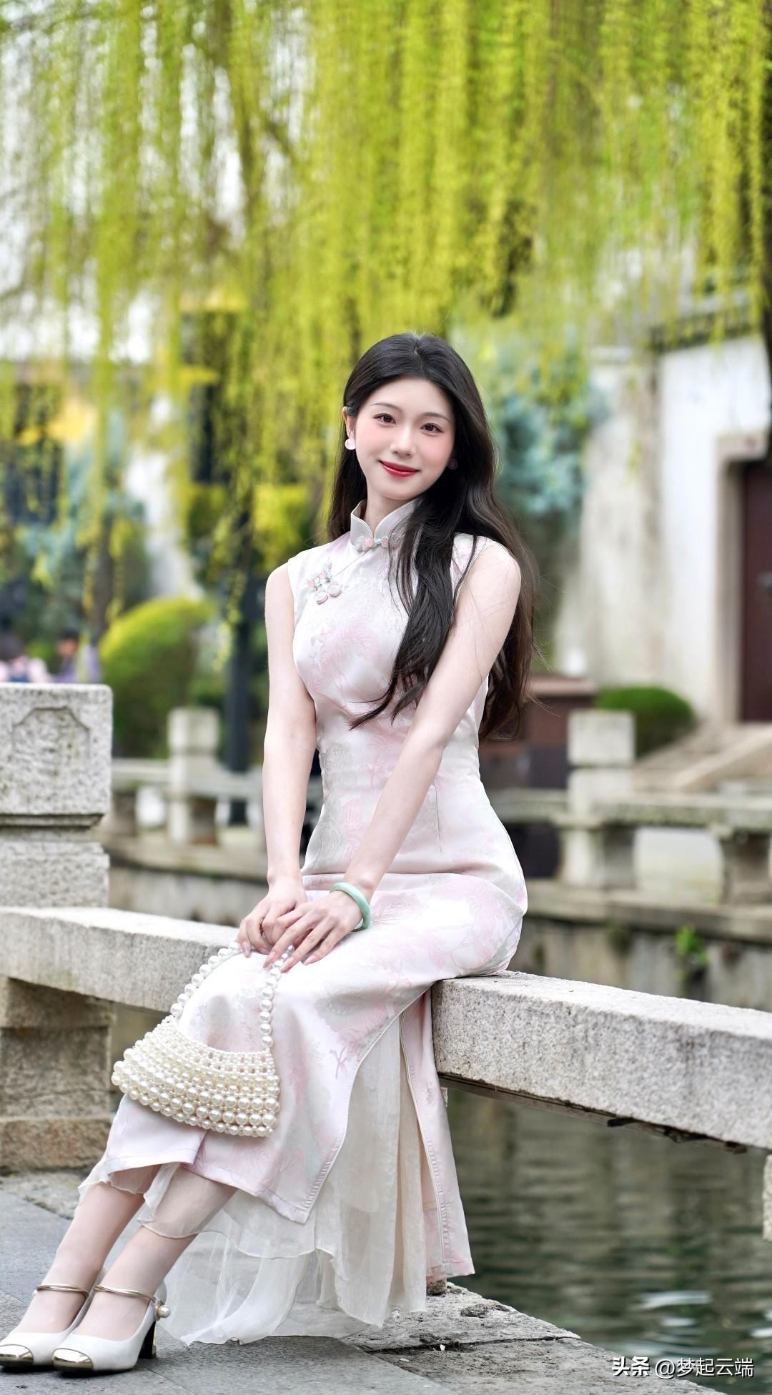 温婉江南女子，水乡桥边静坐，一袭粉色旗袍，尽显古典韵味。