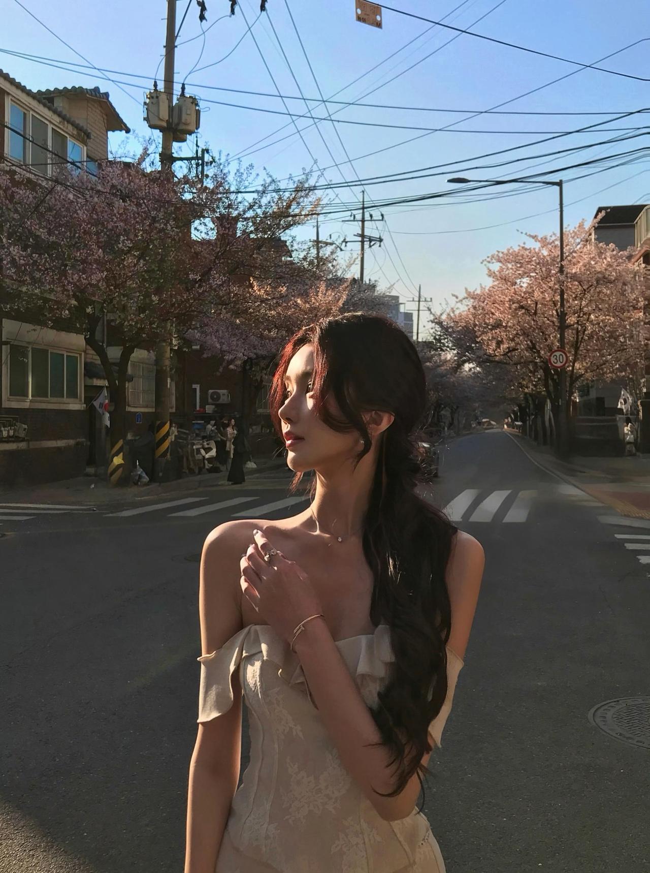 落日余晖穿过樱枝，暖光漫落肩头，
一袭温柔长裙，赴一场春日花事，
风里裹挟着樱花