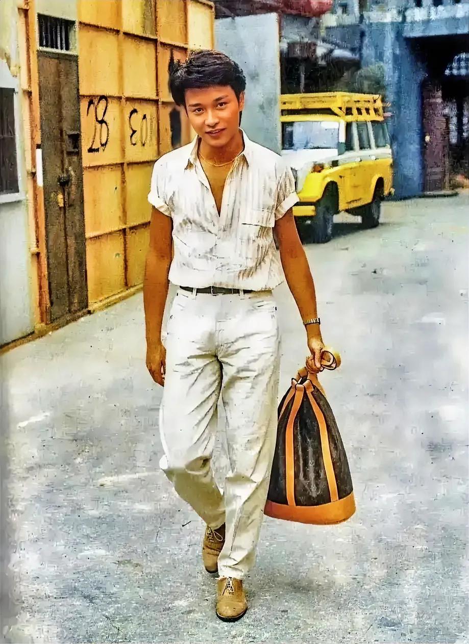 1984年，张国荣拎着LV包包上班。
看这身打扮，应该是走在时尚前列，休闲的，同