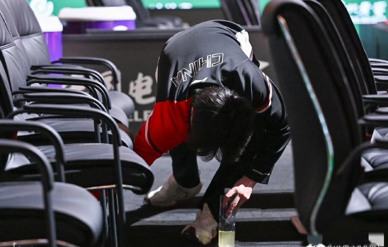 刚拿三项大满贯冠军，累到扶球台喘气的国乒主力，转身蹲地上——不是系鞋带，是捡空水