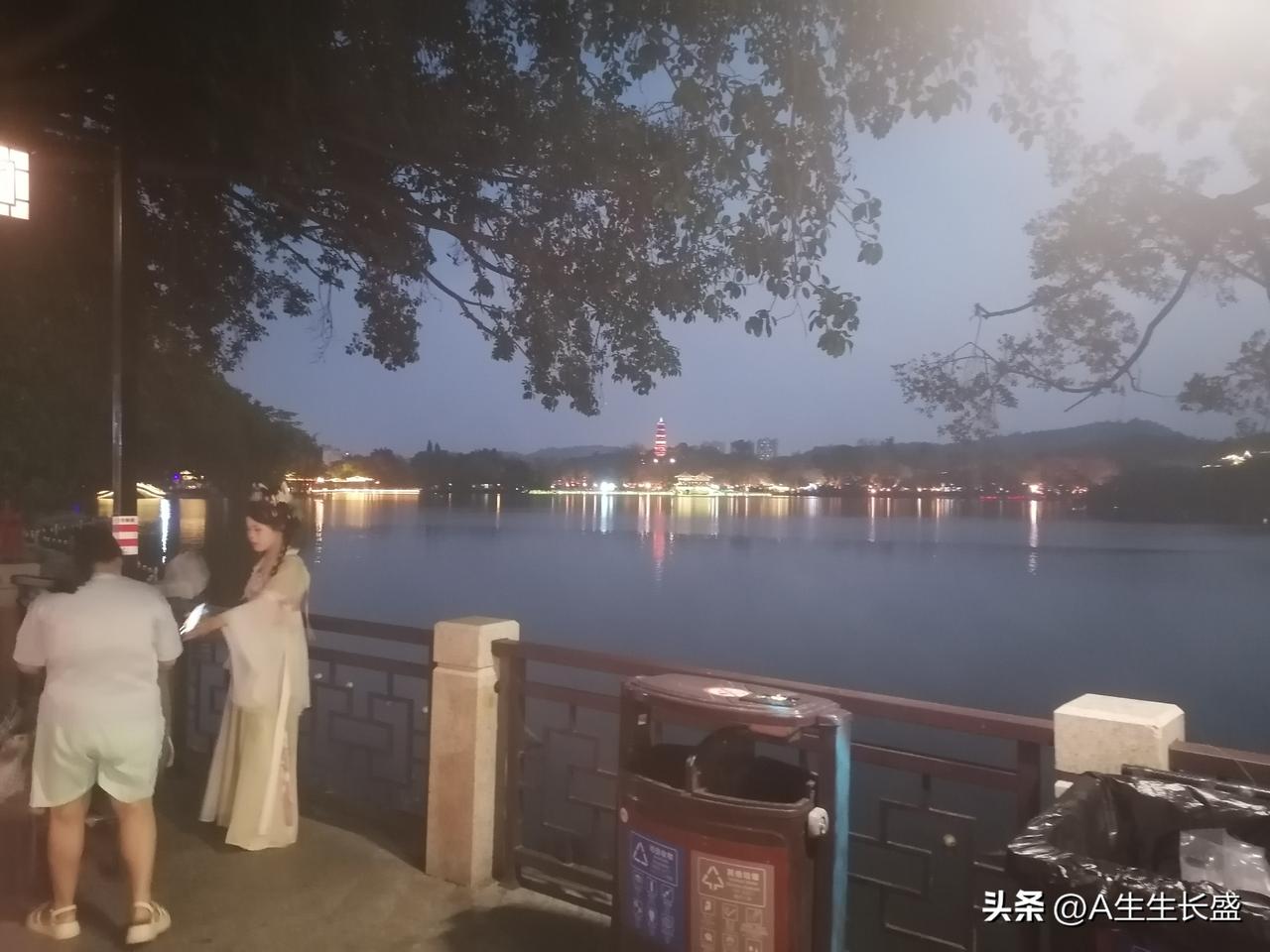 夜色降临，远处天际一片光亮，湖面一片宁静，古塔放射出耀眼红光，古塔下和湖边亭台楼