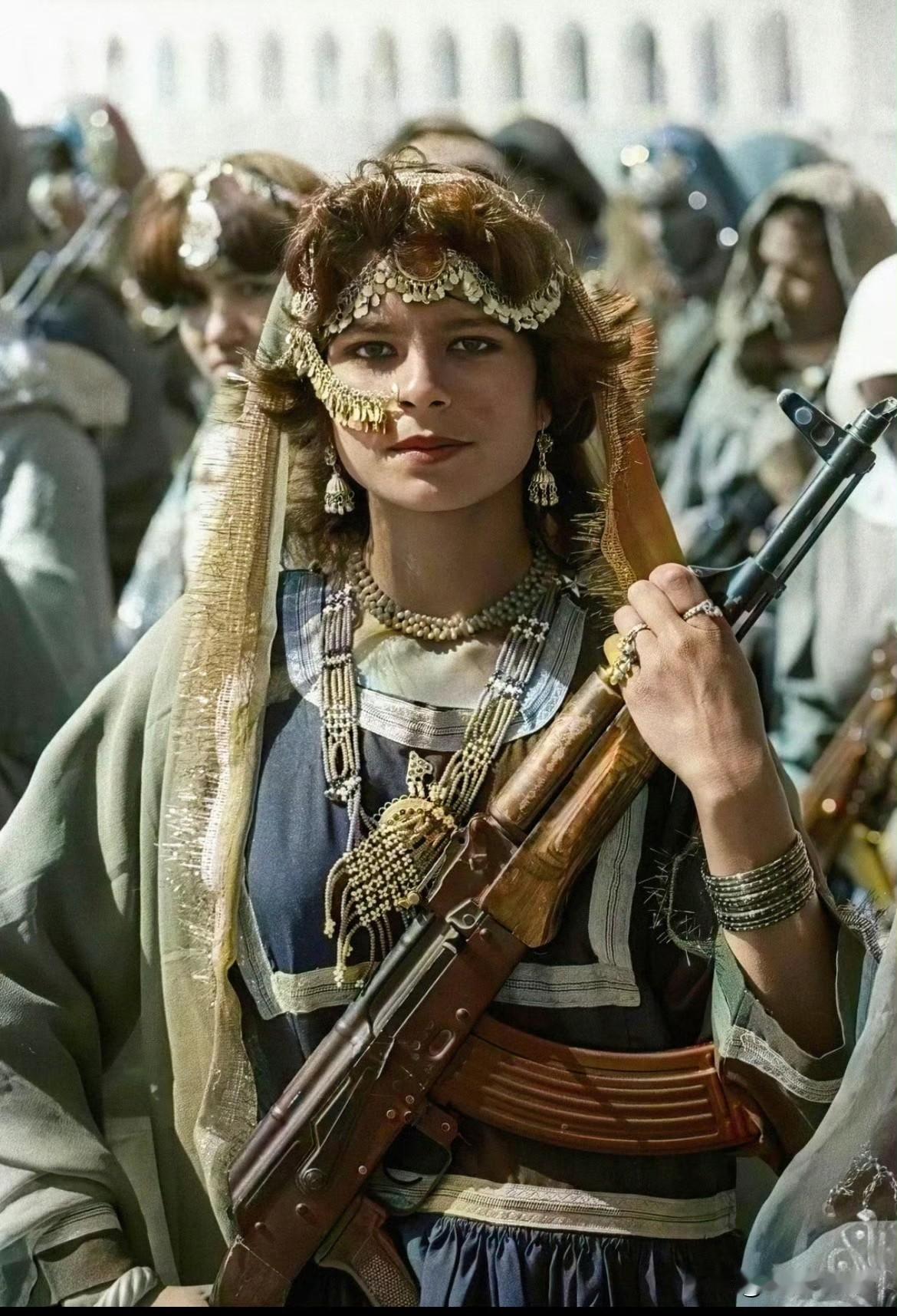 1984年，一名身穿传统服装的阿富汗妇女手持AK47步枪，支持阿富汗民主共和国对