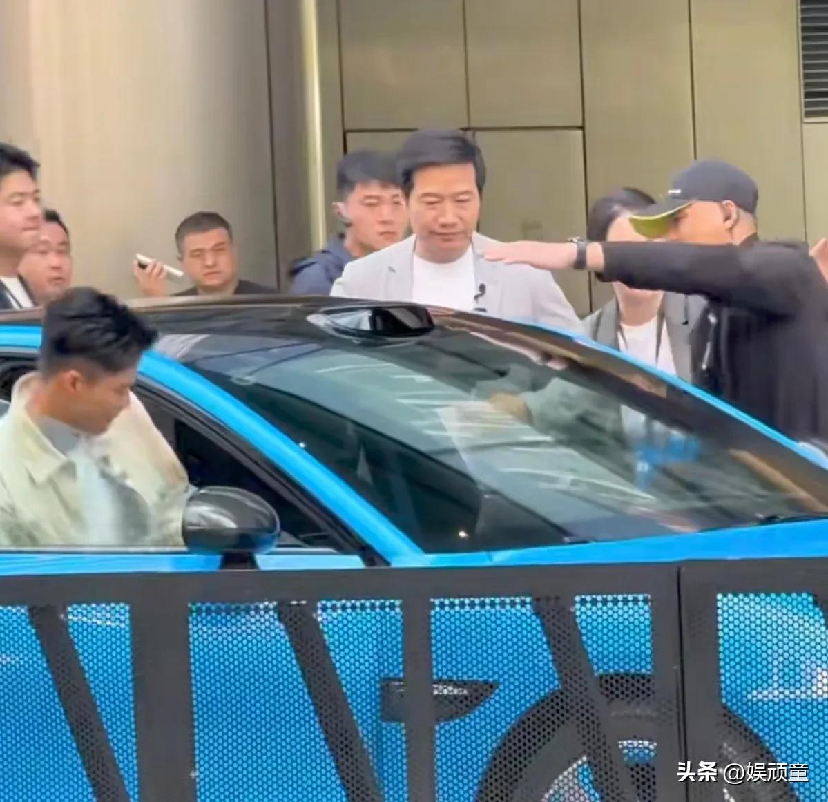 小米汽车，应该不需要有人用手挡住上面，避免碰头！
雷军与苏炳添一起上车时，左边的