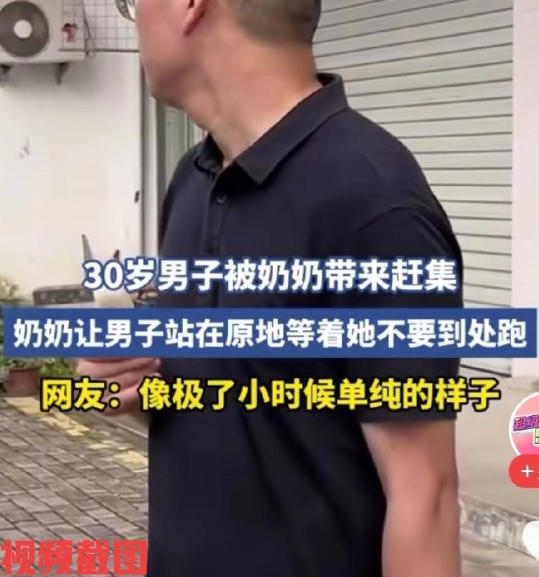 有三十岁男子被奶奶带来赶集。

此刻奶奶让男子站在原地等着她，不要到处乱跑，男子