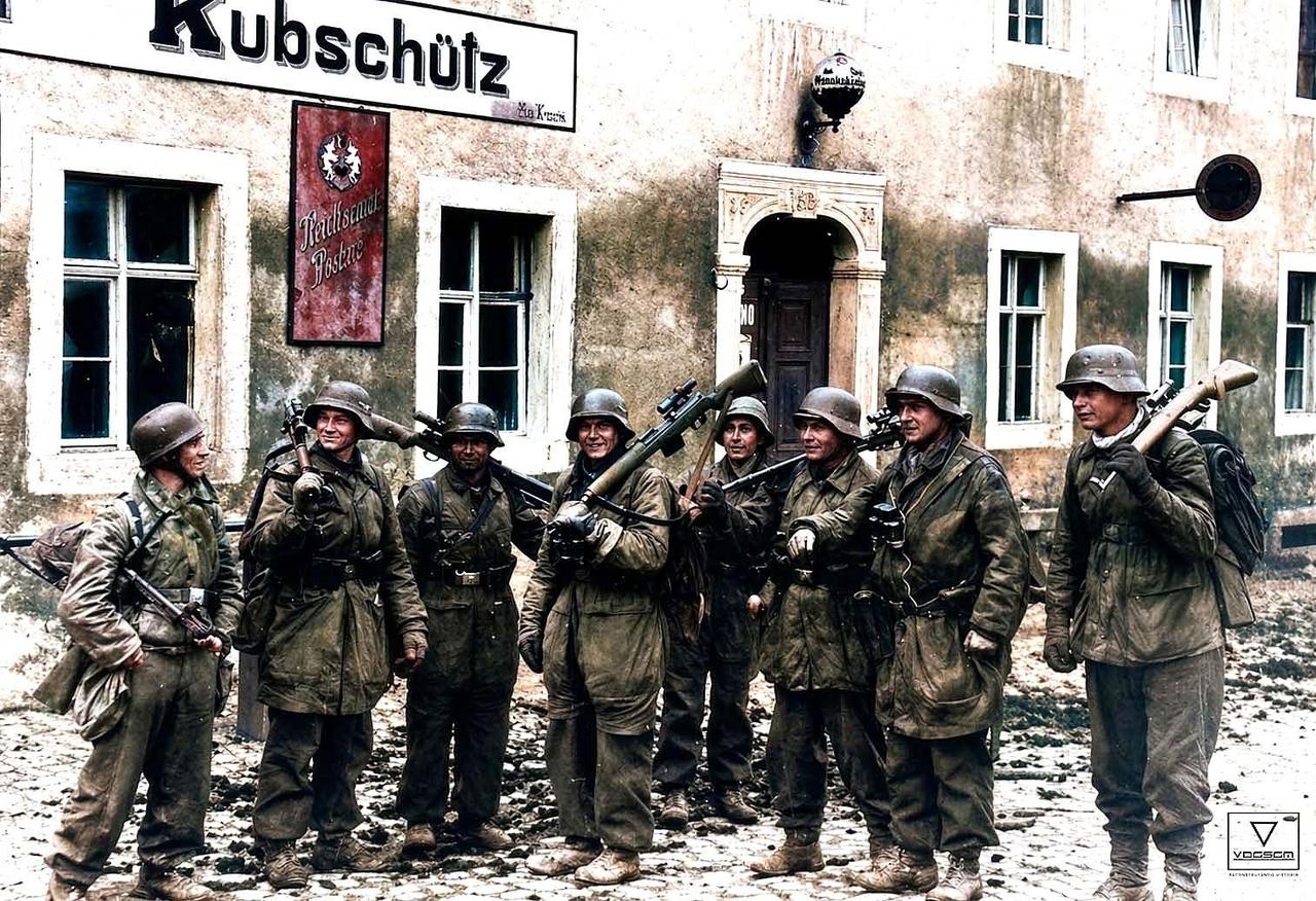 看建筑物上标牌皆为德文，应该是在德国境内。一群德军士兵肩扛狙击枪最左边却站着一名
