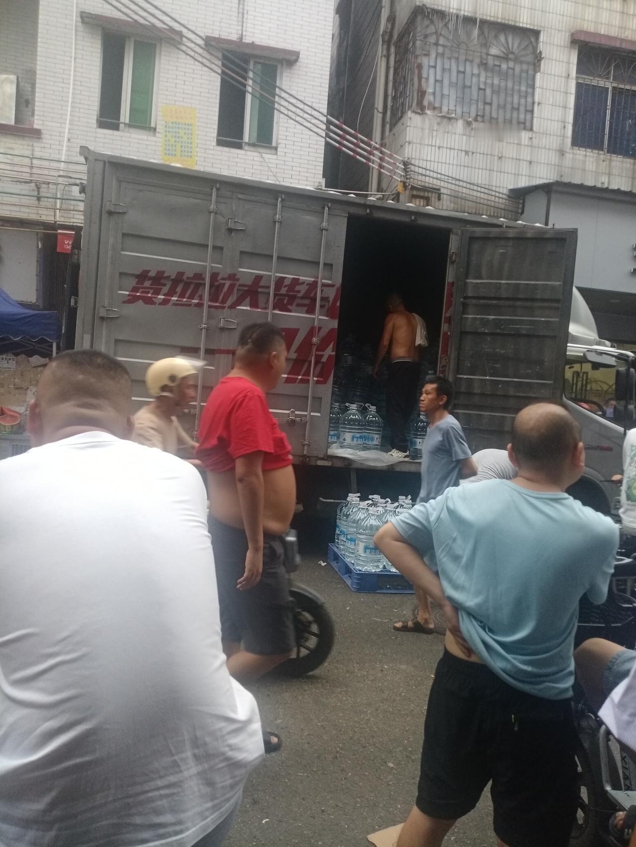 广州桥南新街街头，一辆货车在卸货，里面装的都是大瓶的饮用纯净水，一瓶大纯净水，零