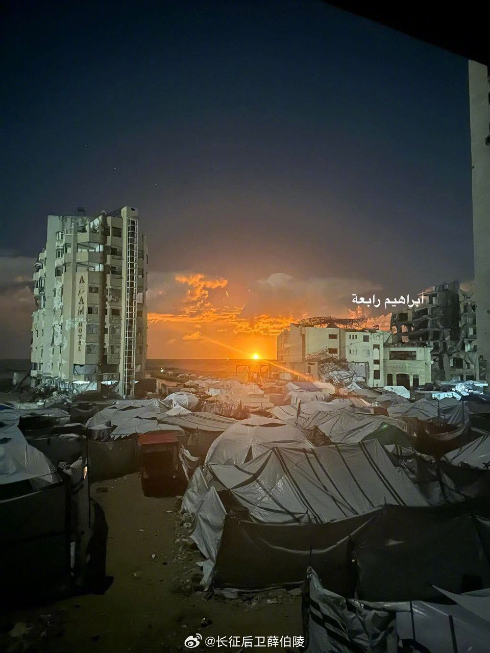 加沙地带，巴勒斯坦难民挤在帐篷里，遥望一艘在加沙海岸附近燃烧的船只。根据伊斯兰革