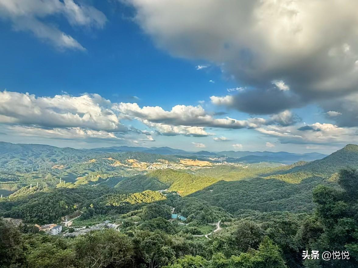 站在山顶往下看，
层层叠叠的山峦像海浪一样铺开，绿色的森林在阳光和云影里忽明忽暗