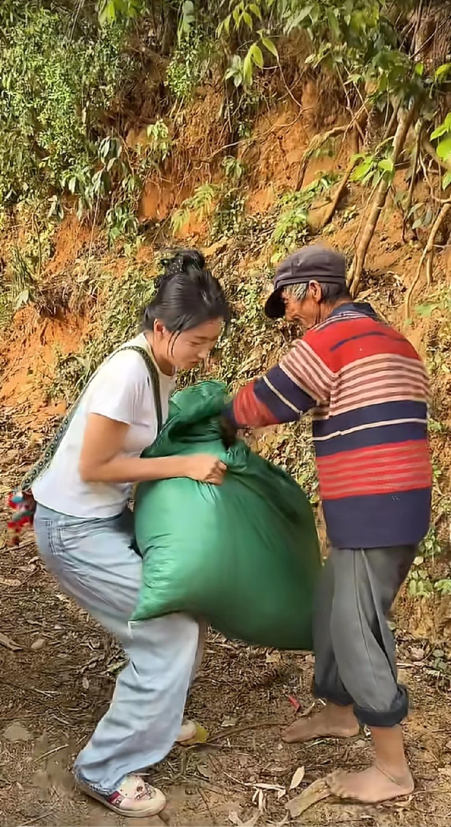 一名女子正开车行驶在乡村公路上，突然看见路边有位白发老人，打着赤脚，扛着重物，接
