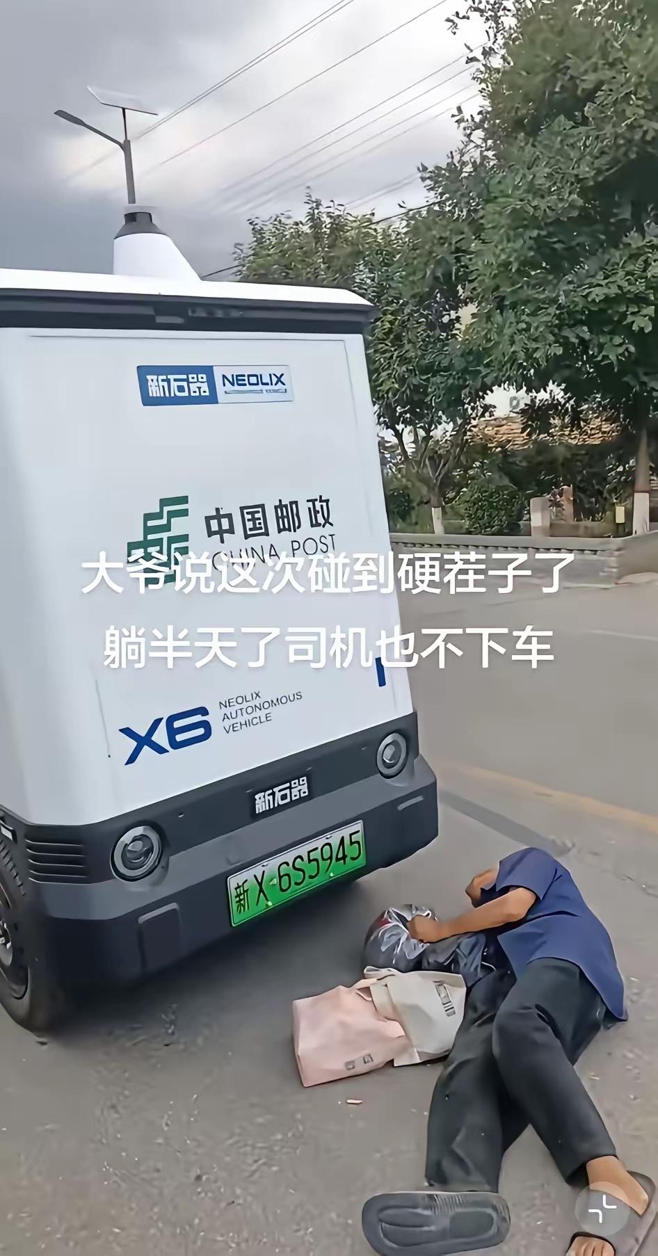 一位大爷躺在一辆无人邮政车的前面，许久过去，也不见司机下车。这时，一位好心人对大