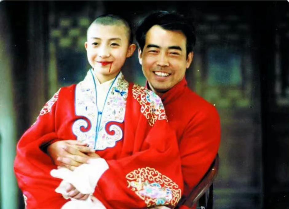 1992年，导演陈凯歌怀中抱着少年程蝶衣的扮演者尹治，一张罕见的留影，尹治身着戏