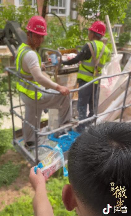 江苏，一工人师傅在窗外施工热得直流汗，没想到的是，在远处的8岁小男孩拆了棒冰袋，