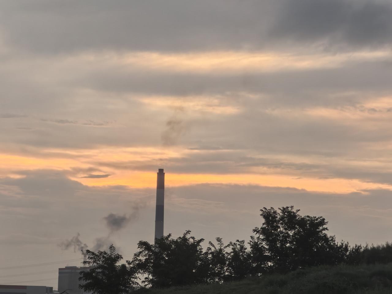 夕阳下，烟囱冒着烟，天色渐暗。