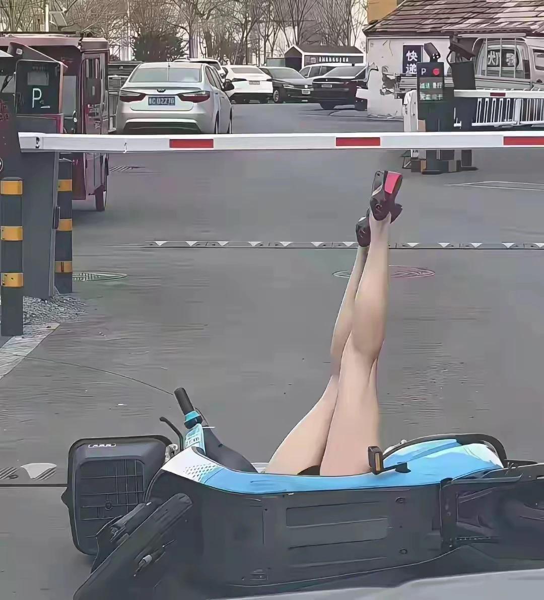 美女骑车实在不小心，翻车摔倒在地上，姿势很优美，一米二大长腿吸引了路人的围观，回