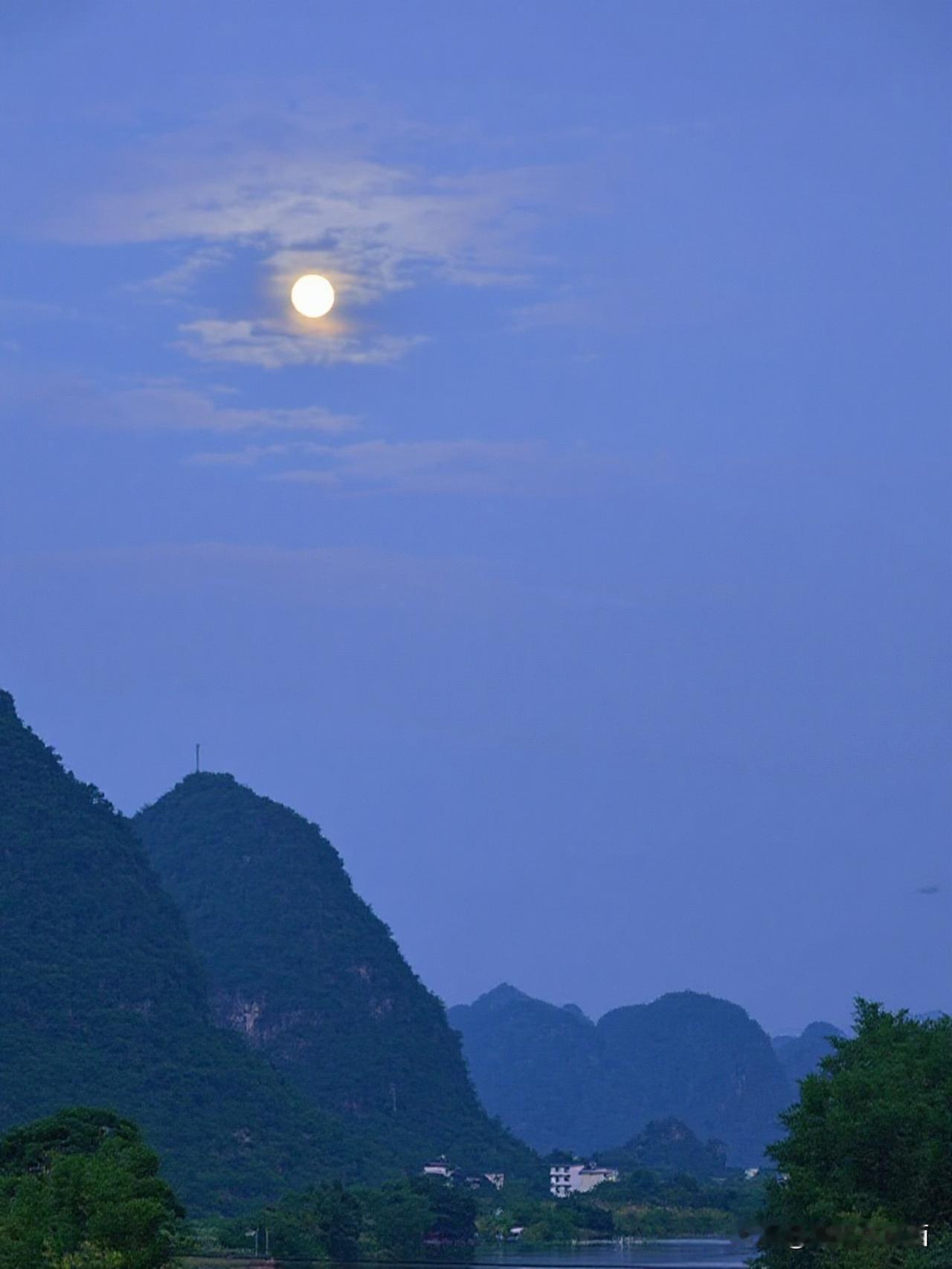 遇龙河月夜
夜游龙河 暮色垂落，圆月悬于青蓝天幕，喀斯特峰林凝翠，遇龙河水静静蜿
