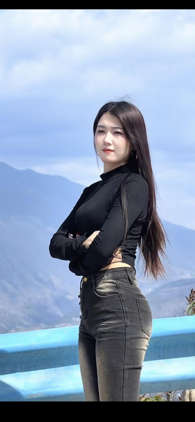 山间少女，黑衣长裤，背对蓝天，享受自由。